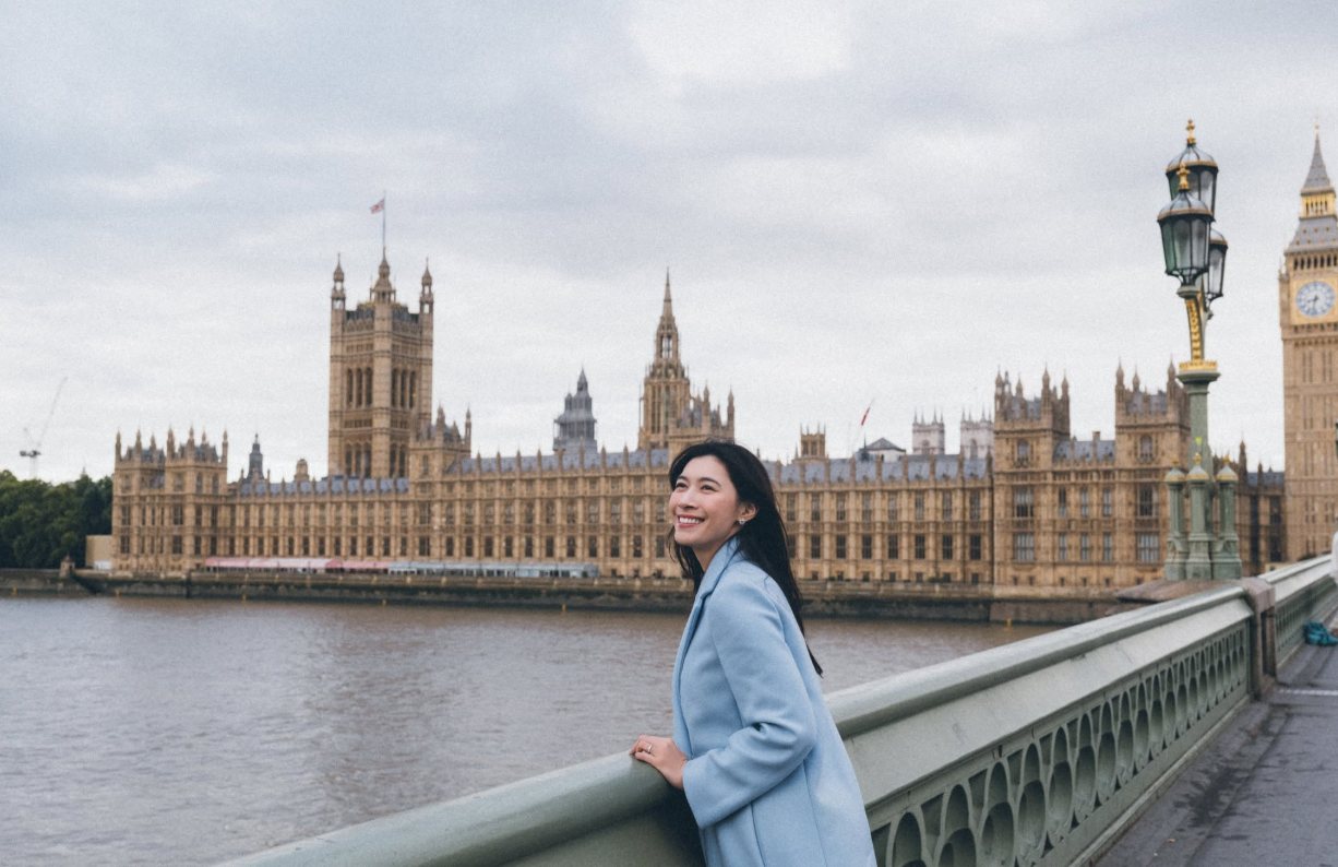 Sylvia mỉm cười trên cầu Westminster, phía sau là Tháp Big Ben và Cung điện Westminster