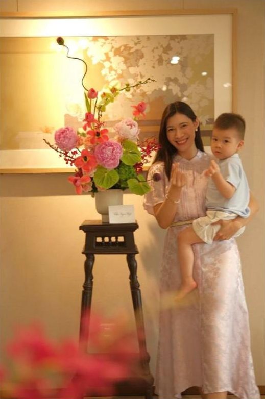 Sylvia bế Uni bên bình hoa tự cắm