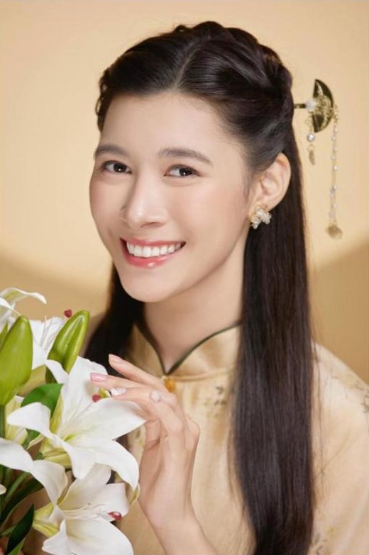Chân dung Sylvia mặc áo dài, cầm bó hoa ly trắng, cười rạng rỡ